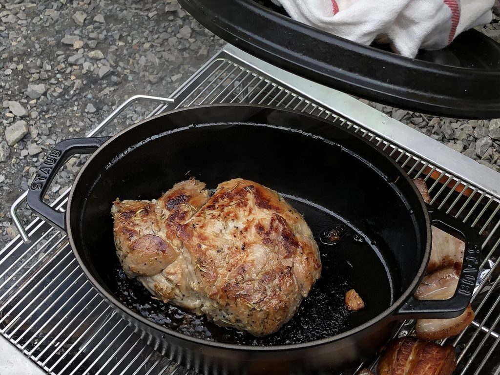 BBQコンロの上でダッチオーブンを使って肉を焼く