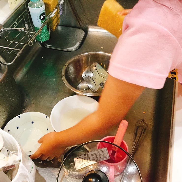 お皿洗いをお手伝いする子供