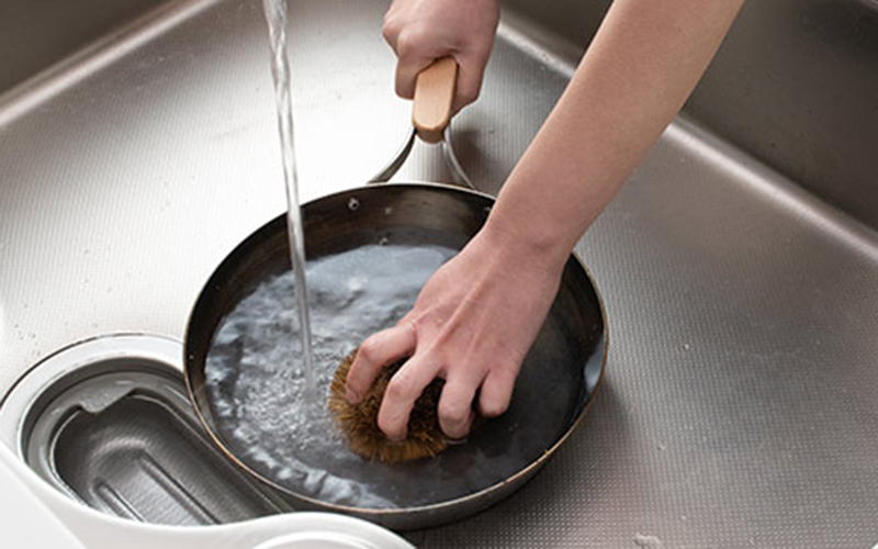 鉄フライパンをお湯とたわしで洗う