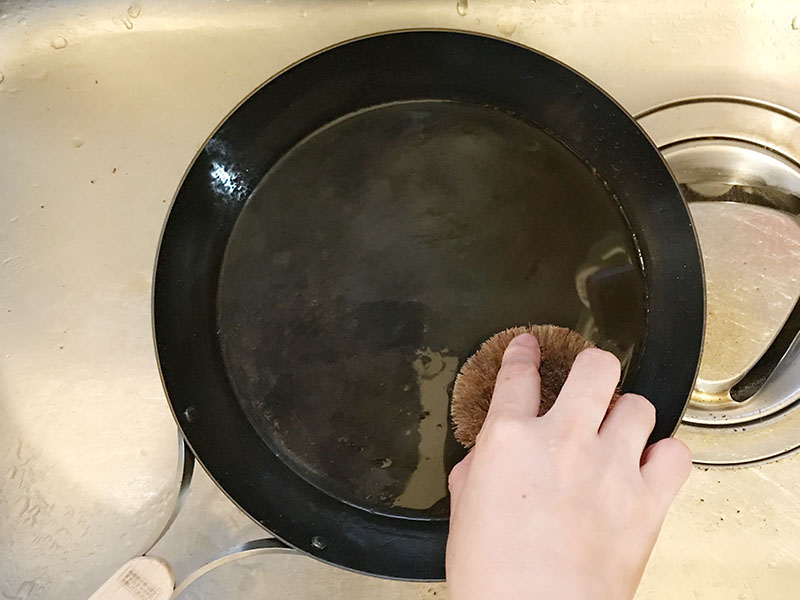 鉄フライパンをたわしで洗う