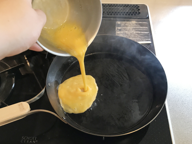 油をなじませた鉄フライパンに溶き卵を入れる